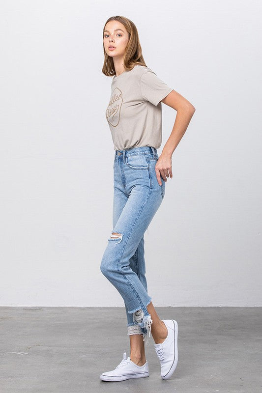 High-waist tapered jeans with ripped knee and frayed hem in medium-wash denim