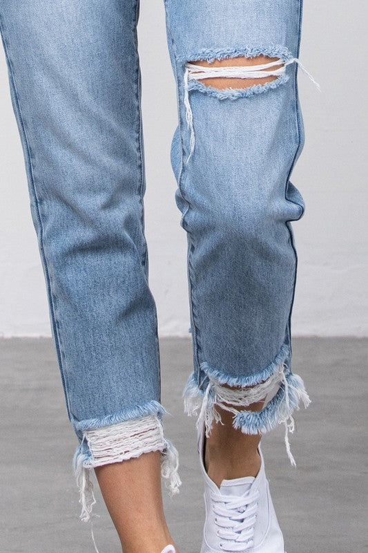 Medium-wash high-waist ripped tapered jeans with frayed hem and knee cutout