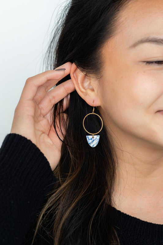 Gold hoop earring with blue patterned drop on ear