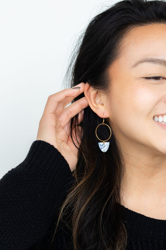 Gold hoop earring with blue patterned drop charm, worn with hair tucked back