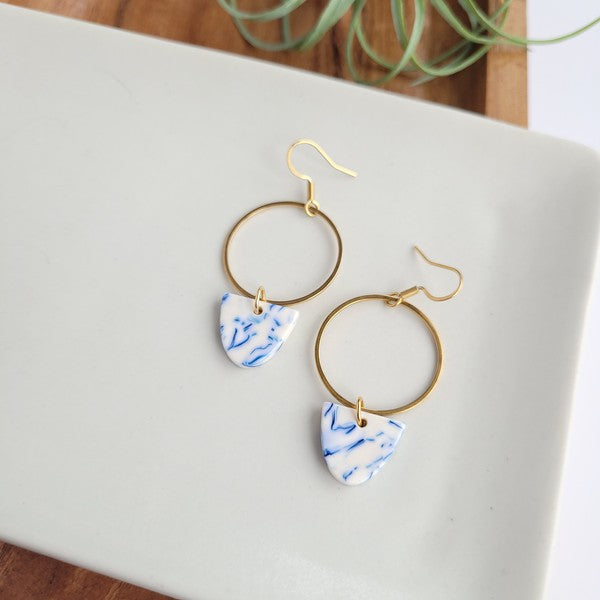 Close-up: gold hoop earrings with blue patterned drops, hanging hooks
