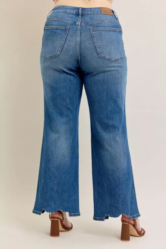 Mid-wash back of wide-leg jeans with center seam, pockets, and destroyed hem