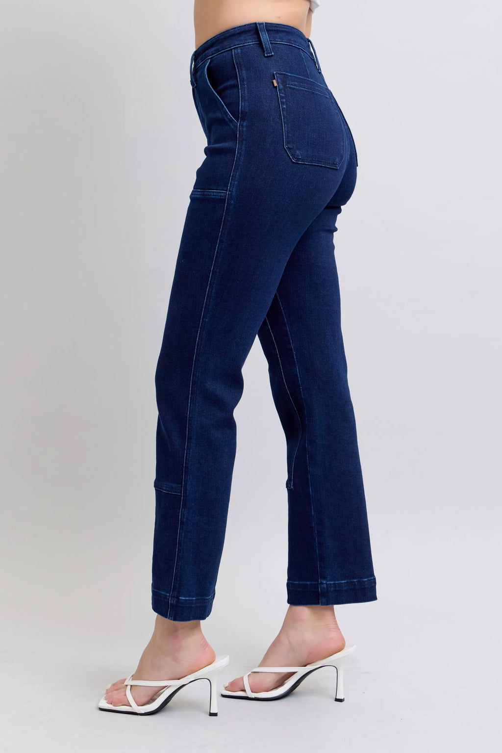 Dark blue straight jeans, side profile, mid-rise with knee patch detail.