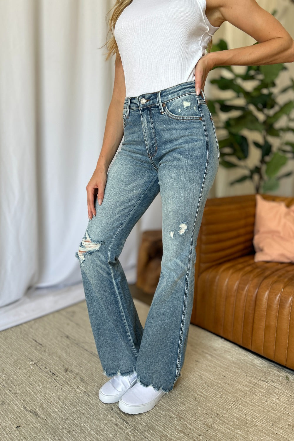 Front view of medium wash destroyed flare jeans with ripped knees and frayed leg openings