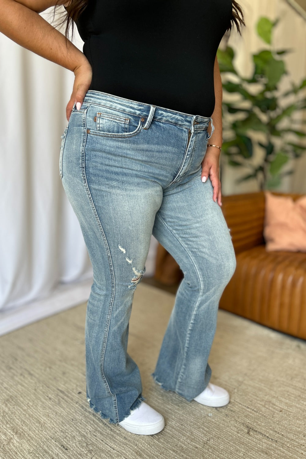Light-wash mid-rise bootcut flare jeans with front knee rips and whisker fading