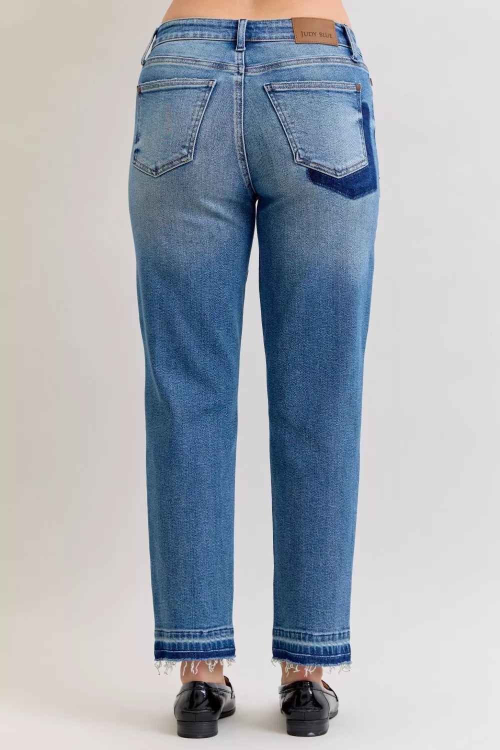 Medium blue mid-rise jeans from back: two back pockets and frayed release hem