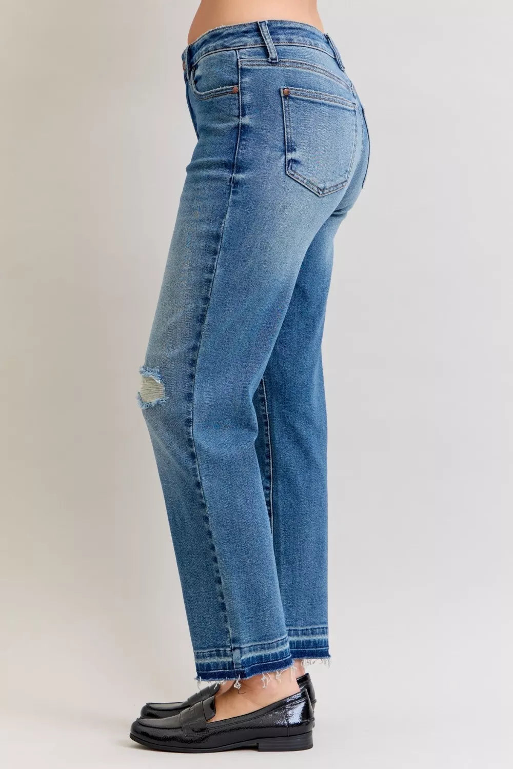 Rear side view: medium blue mid-rise jeans with repair patch at lower leg