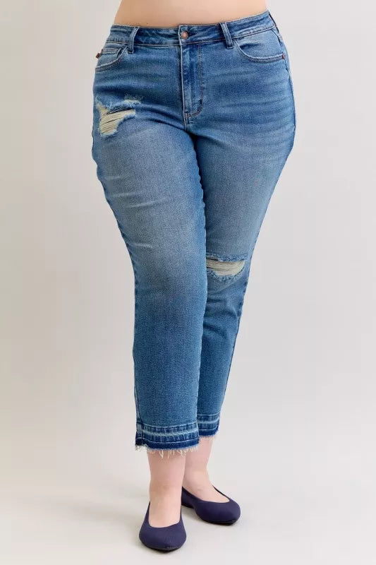 Cropped three-quarter front view of medium blue mid-rise jeans with knee distress