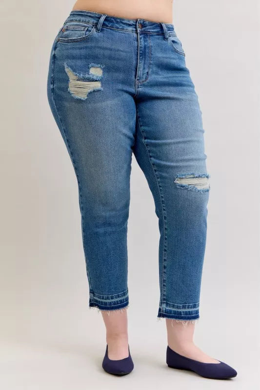 Front view: medium blue mid-rise jeans with torn knee areas and release hem cuffs