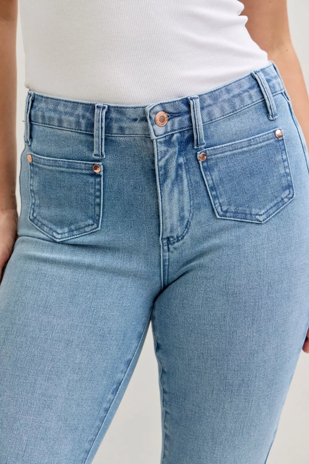 Light blue denim close-up: mid-rise waistband, front patch pockets, contrast wash