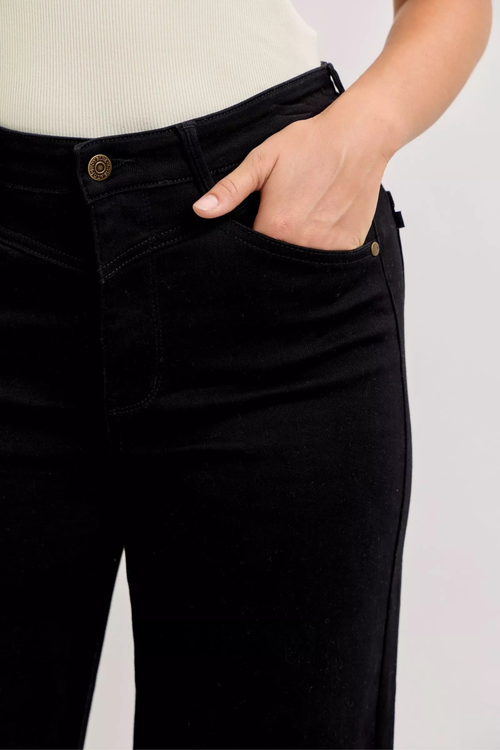 Black denim waistband close-up, button and zip fly with belt loops