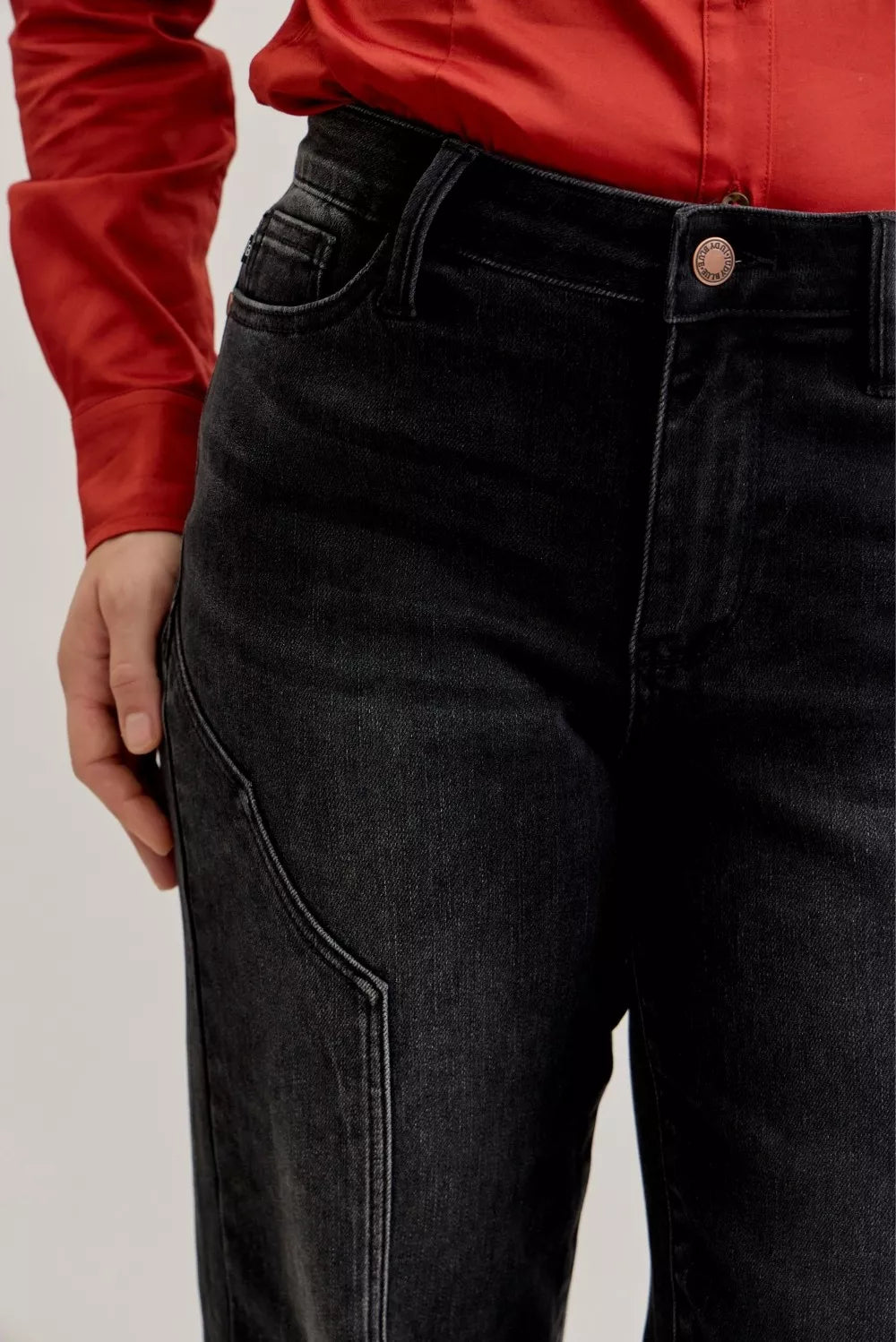 Black jeans with western seam detail, close-up of front thigh seam and pocket