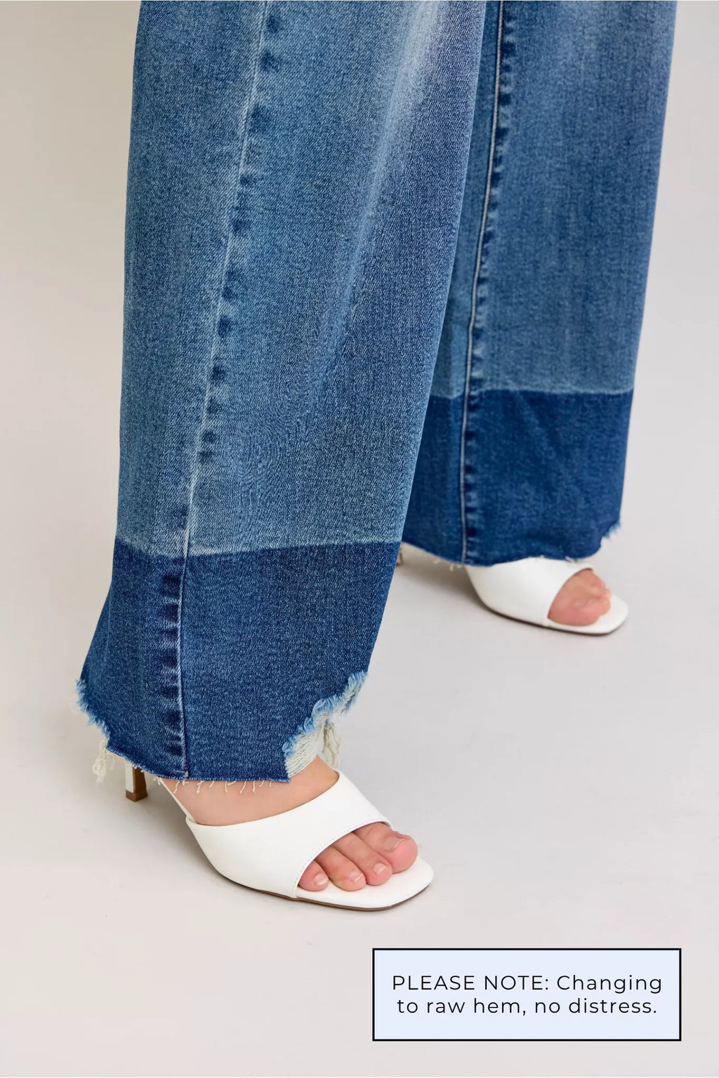 Raw-hem detail on dark wash (DK) straight jeans with open frayed edge