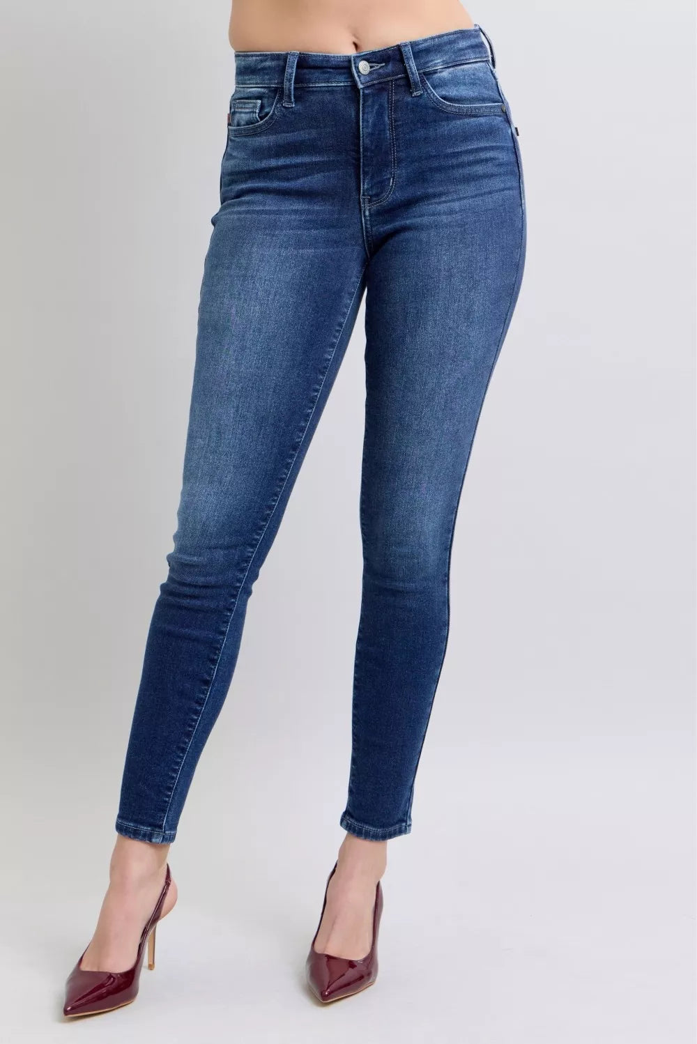 Dark blue skinny jeans with belt loops, button fly, and slim leg fit