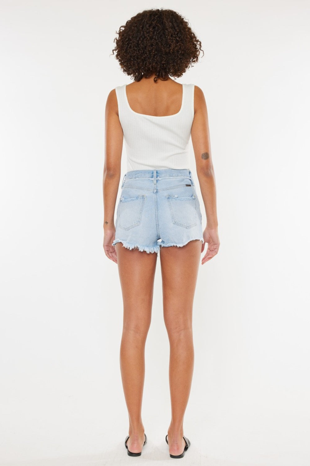 Espalda de shorts de mezclilla azul medio desgastados con dobladillo deshilachado