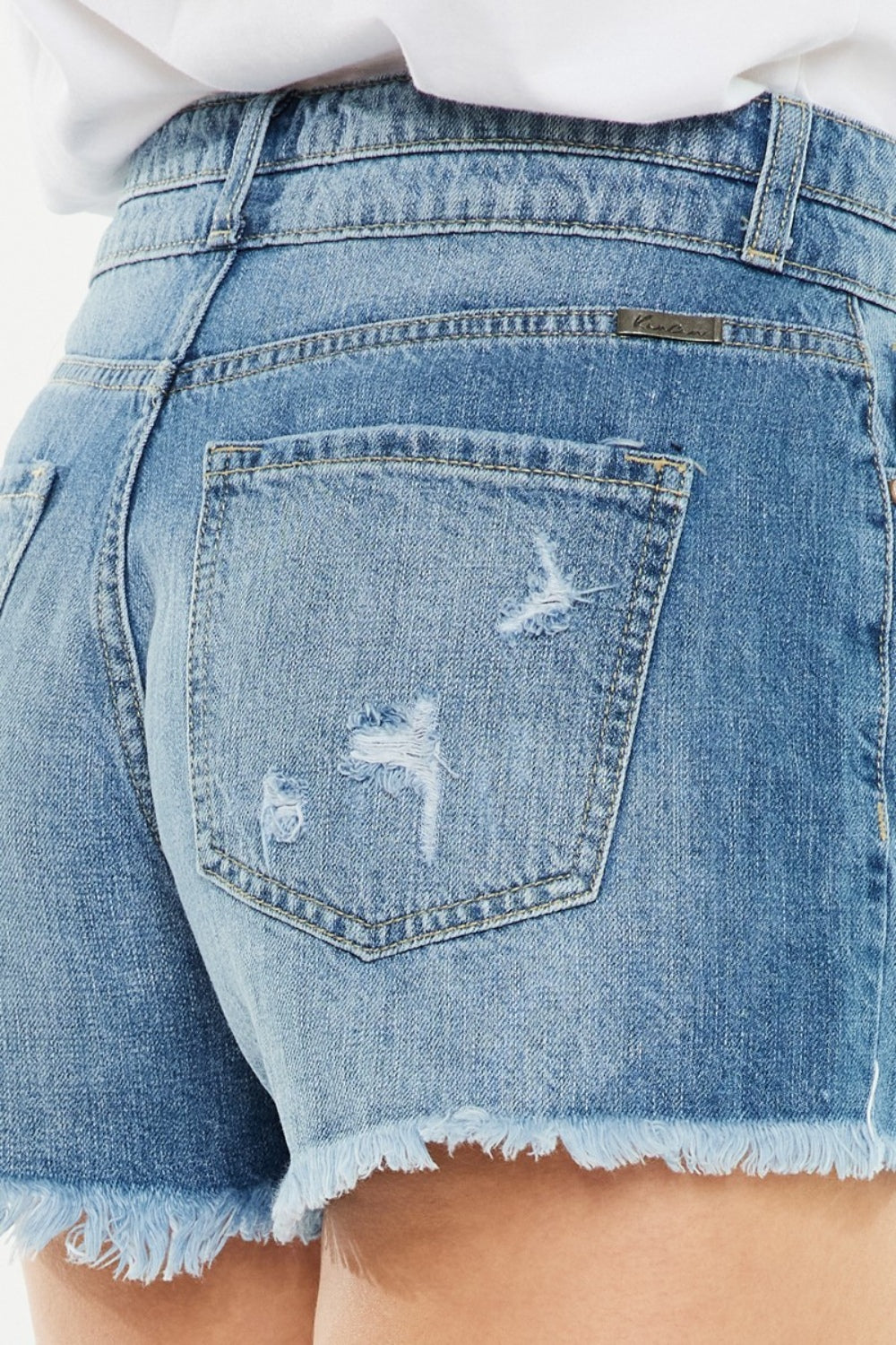 Back view of medium-blue denim shorts with high-rise waist, distressed back pocket