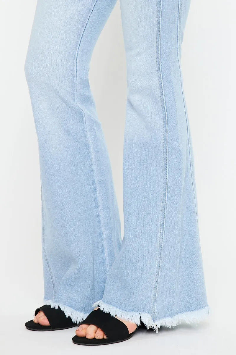 Close-up of light wash flared jeans hem with frayed edge and black slide sandals