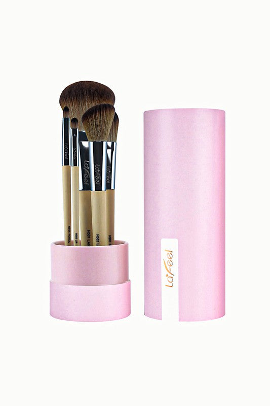 Brush set in pink holder: five beige-handled brushes with dark bristles beside tube