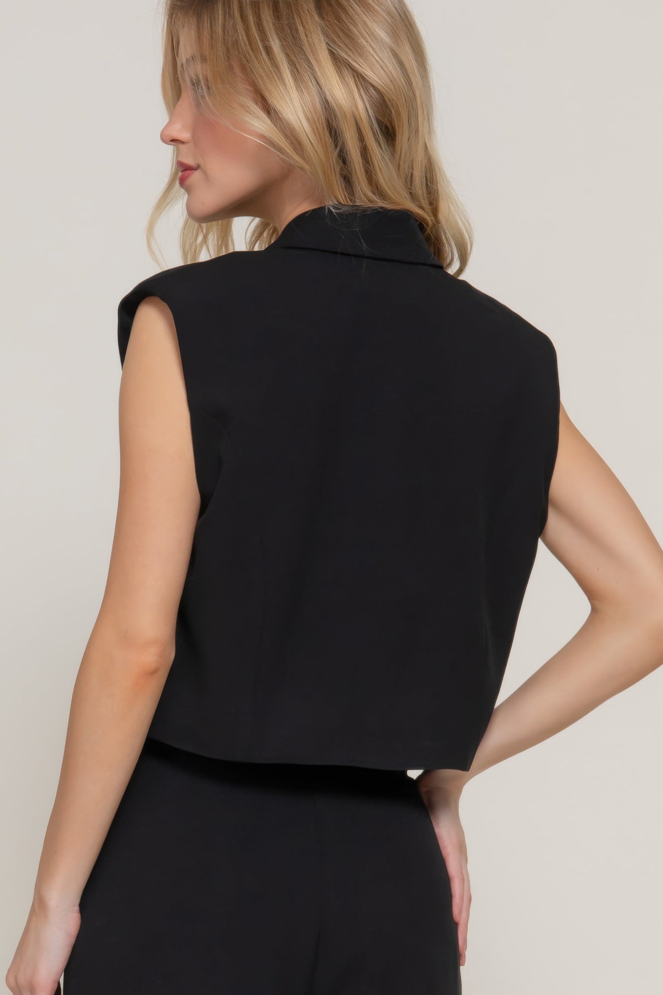 Back view of black sleeveless vest with structured shoulder yoke