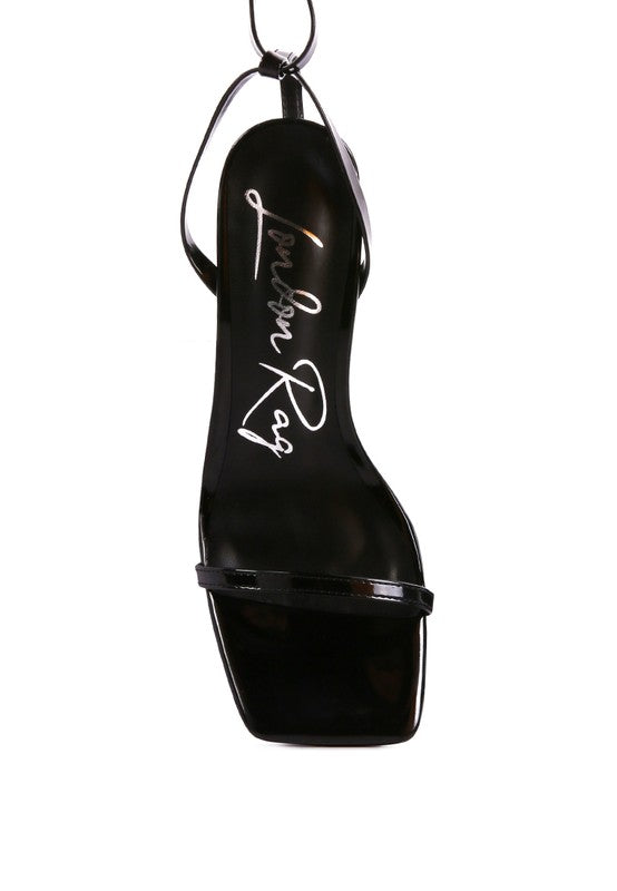 Black strappy tie-up spool heel sandal, close-up of thong-style foot strap