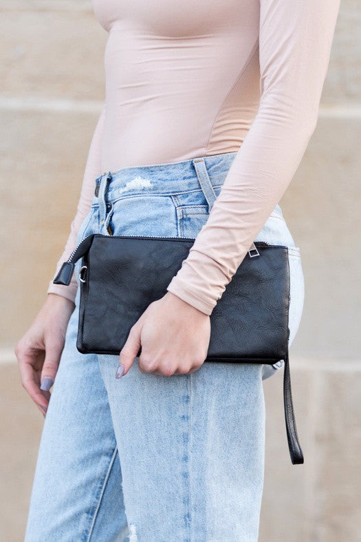 Liv Convertible Compact Crossbody in dark leather-look, hands holding front zip pocket