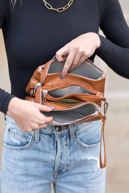 Cognac crossbody bag open to show interior, top zipper and multiple inner compartments