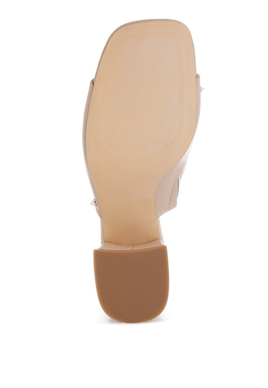 Beige side view of block-heel mule with stud accents; outsole visible