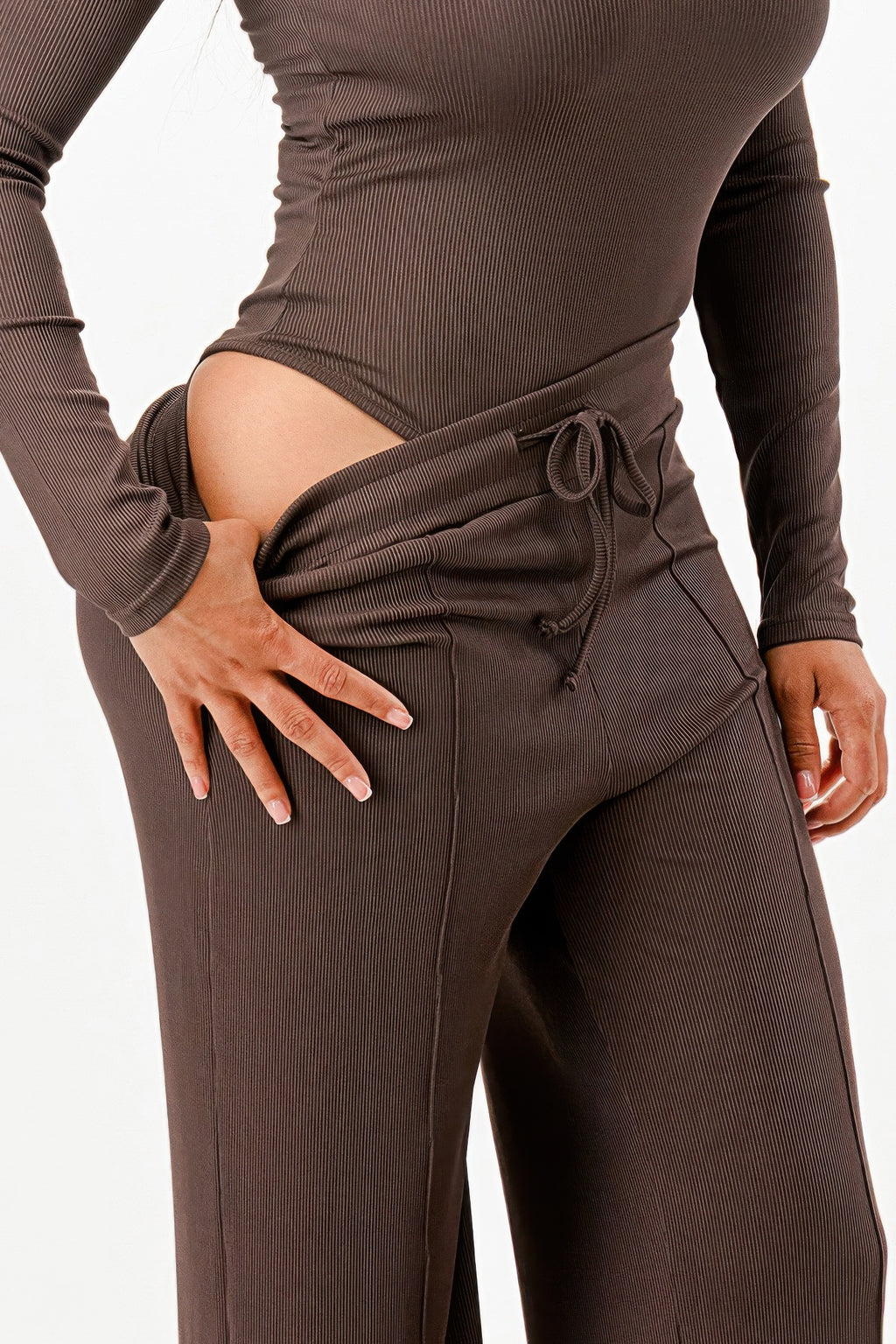 Close-up of dark brown ribbed pants: drawstring waist and wide-leg seam detail