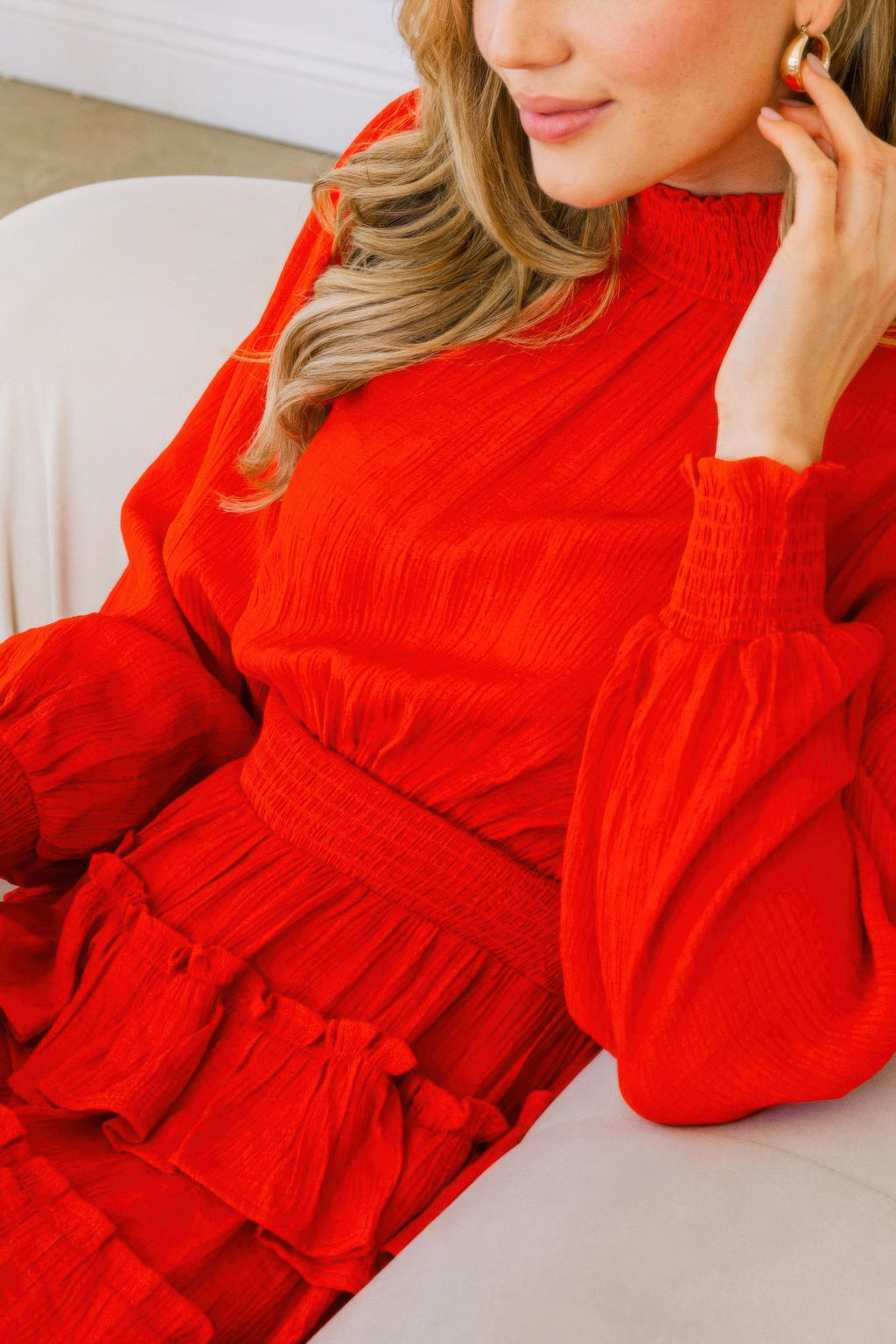 Close-up of red smocked neckline and long sleeves on tiered ruffle mini dress