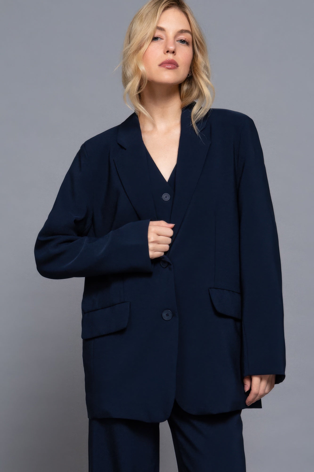 Navy blazer front view: single-breasted button closure, notch lapels, patch pockets.