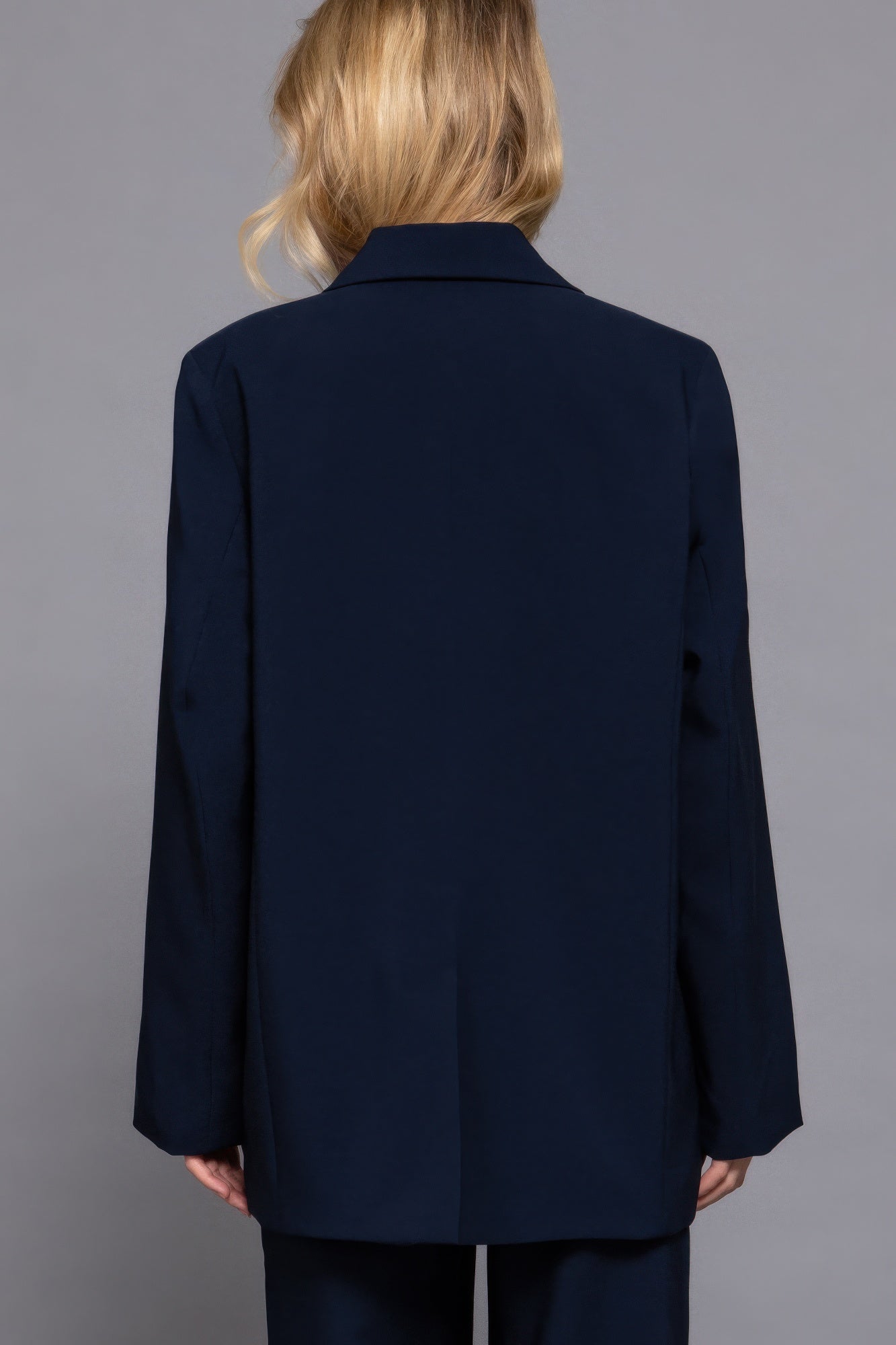 Back view of navy long-sleeve blazer with structured shoulders and full-length hem.