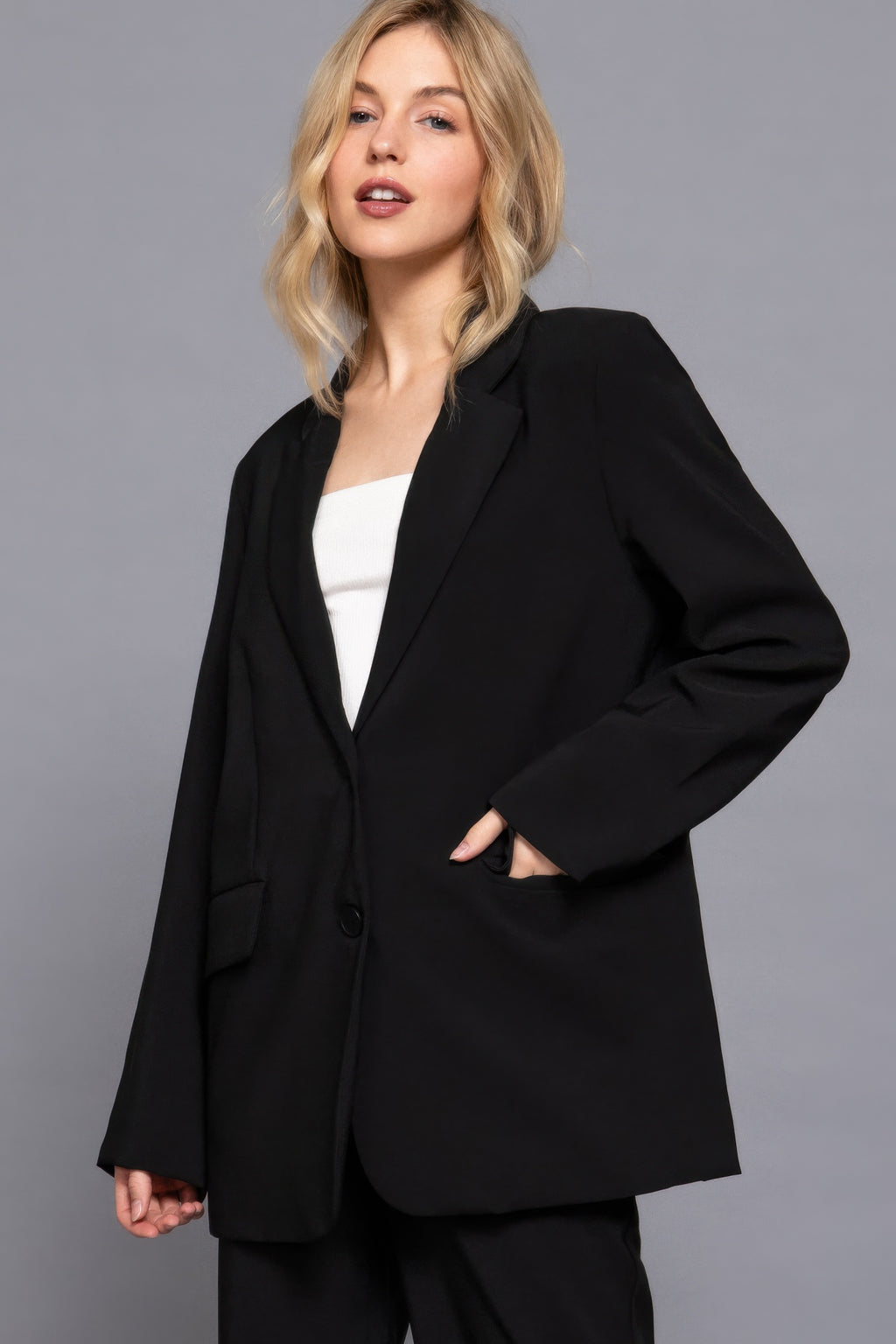 Black long blazer with front button closure and flap pockets, long sleeves.