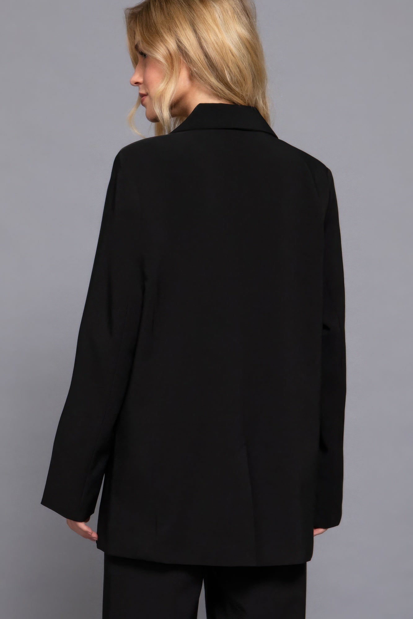 Back view of black long-sleeve blazer with structured shoulders and straight hem.