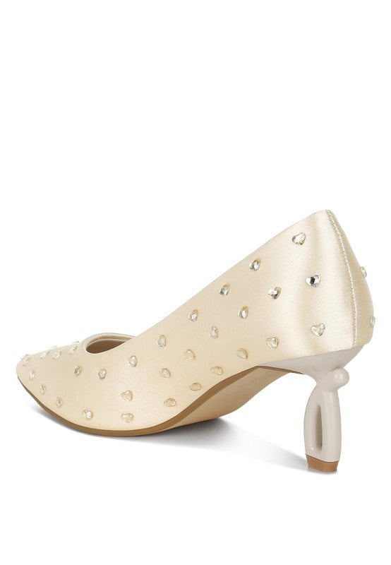Beige pointed-toe pump showing the heel and heart-shaped rhinestone pattern
