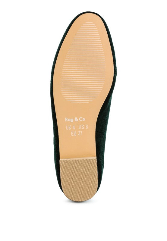 Bottom view of dark green velvet loafer sole with tan rubber base