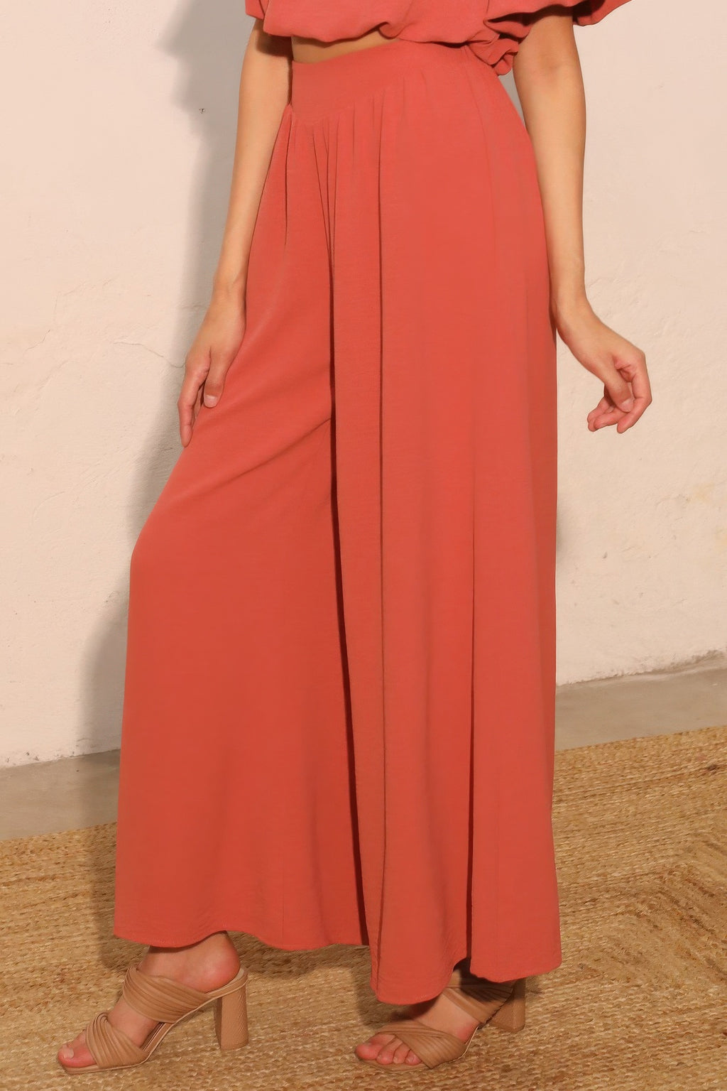 Rust wide-leg swing pants showing vertical pleats and wide, relaxed legs
