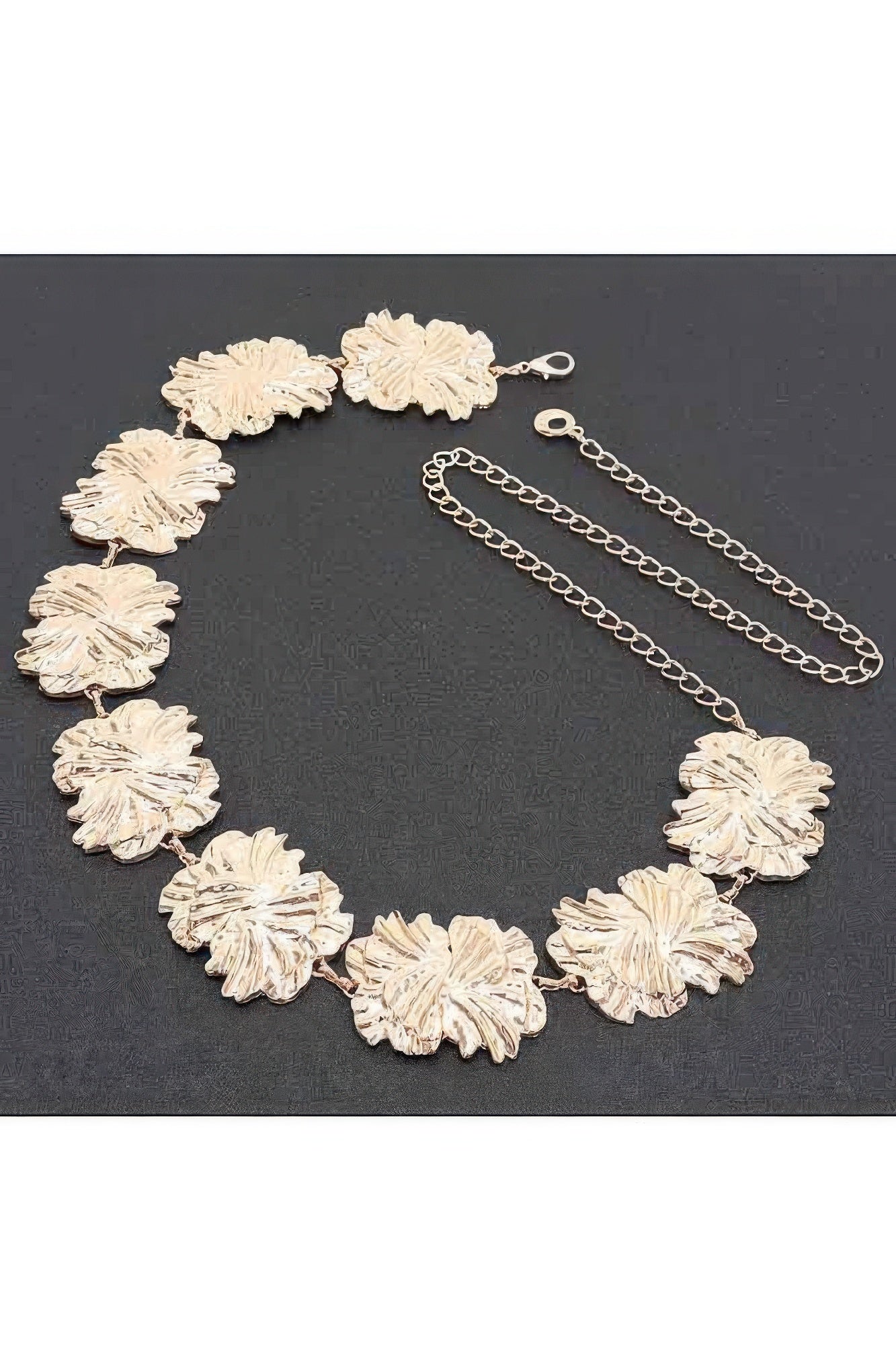 Gold metal chain belt laid flat, textured flower links with clasp and extender