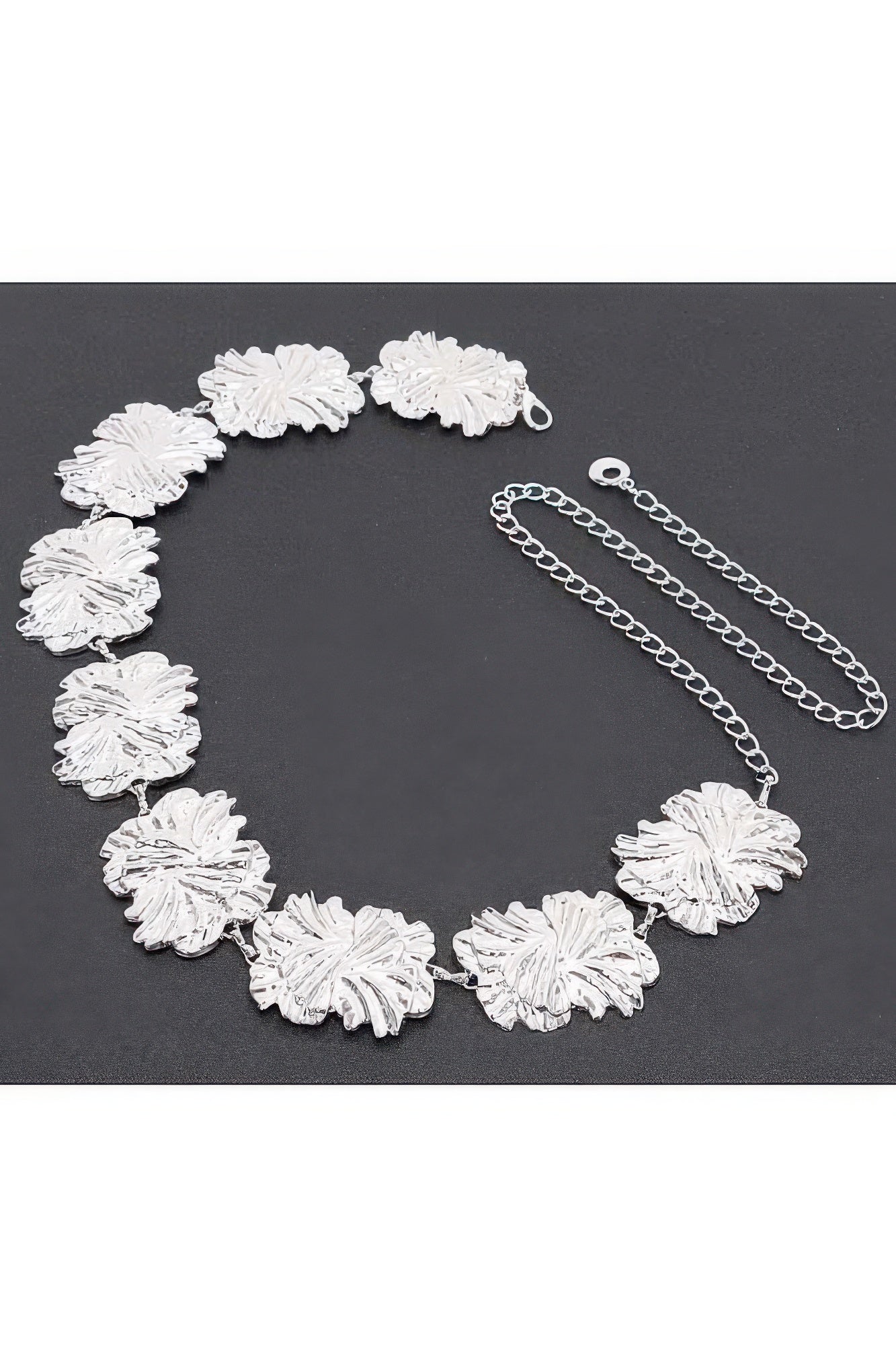 Silver metal chain belt laid flat, textured flower medallions with chain extender