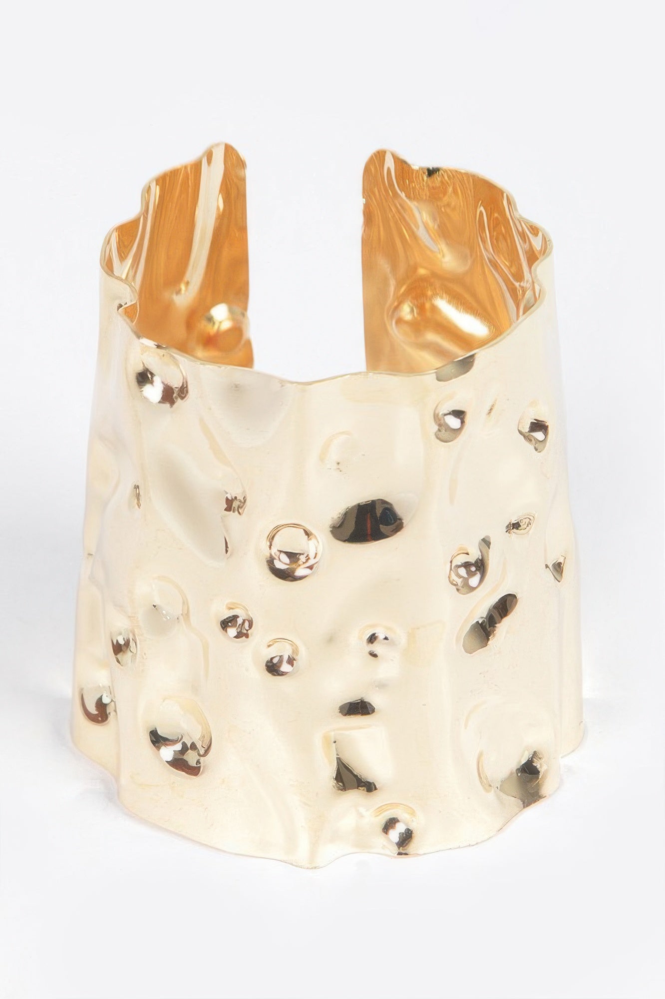 Metal cuff in gold tone with irregular openwork texture and small stud details