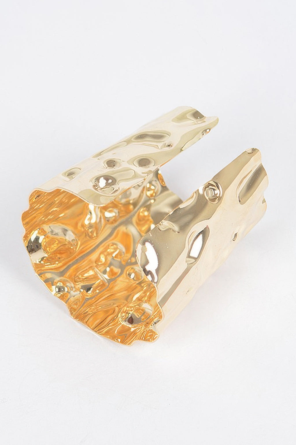 Gold metal cuff, side view with hammered texture and circular cutout details