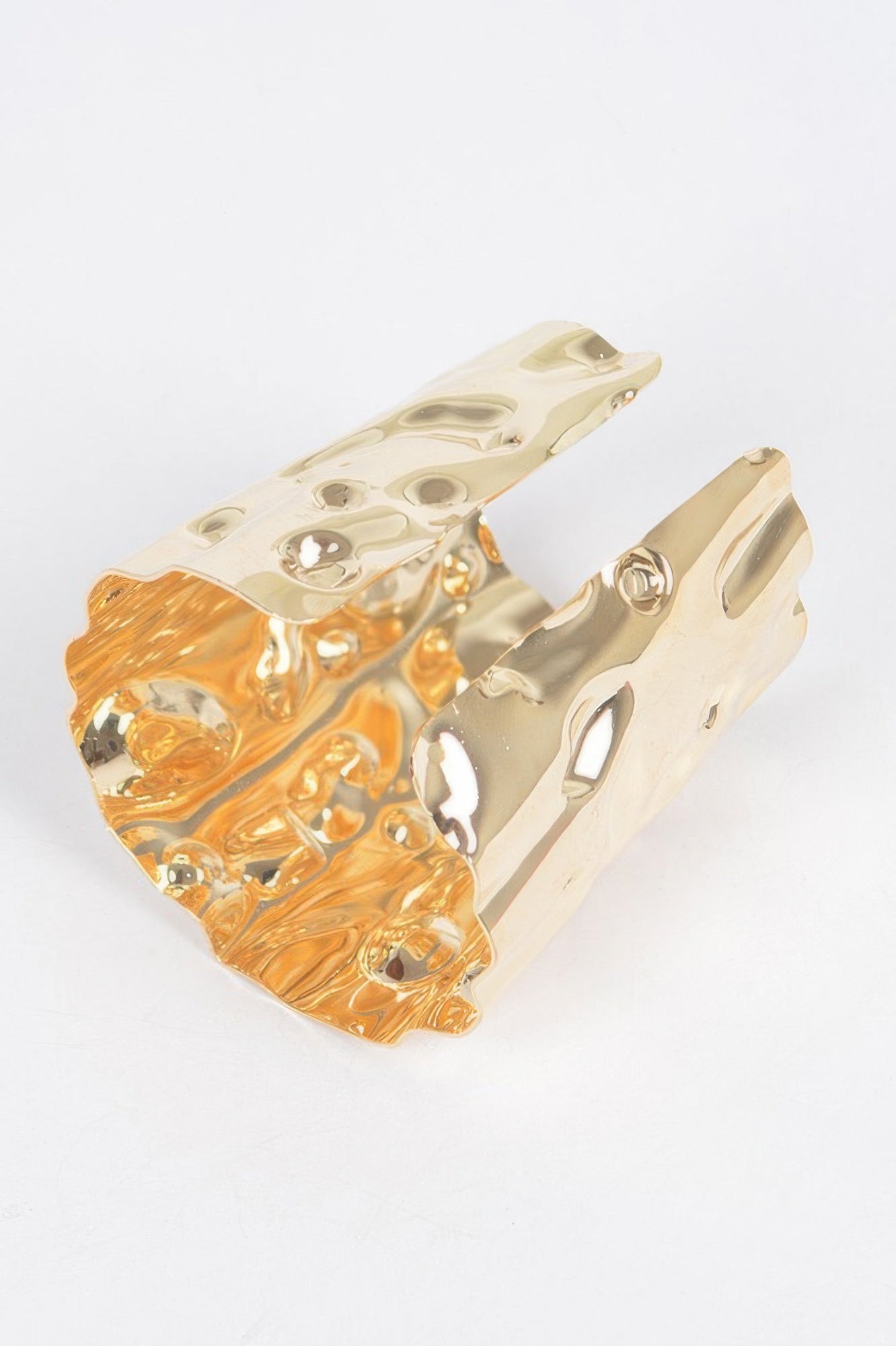 Gold metal cuff, side view with hammered texture and circular cutout details