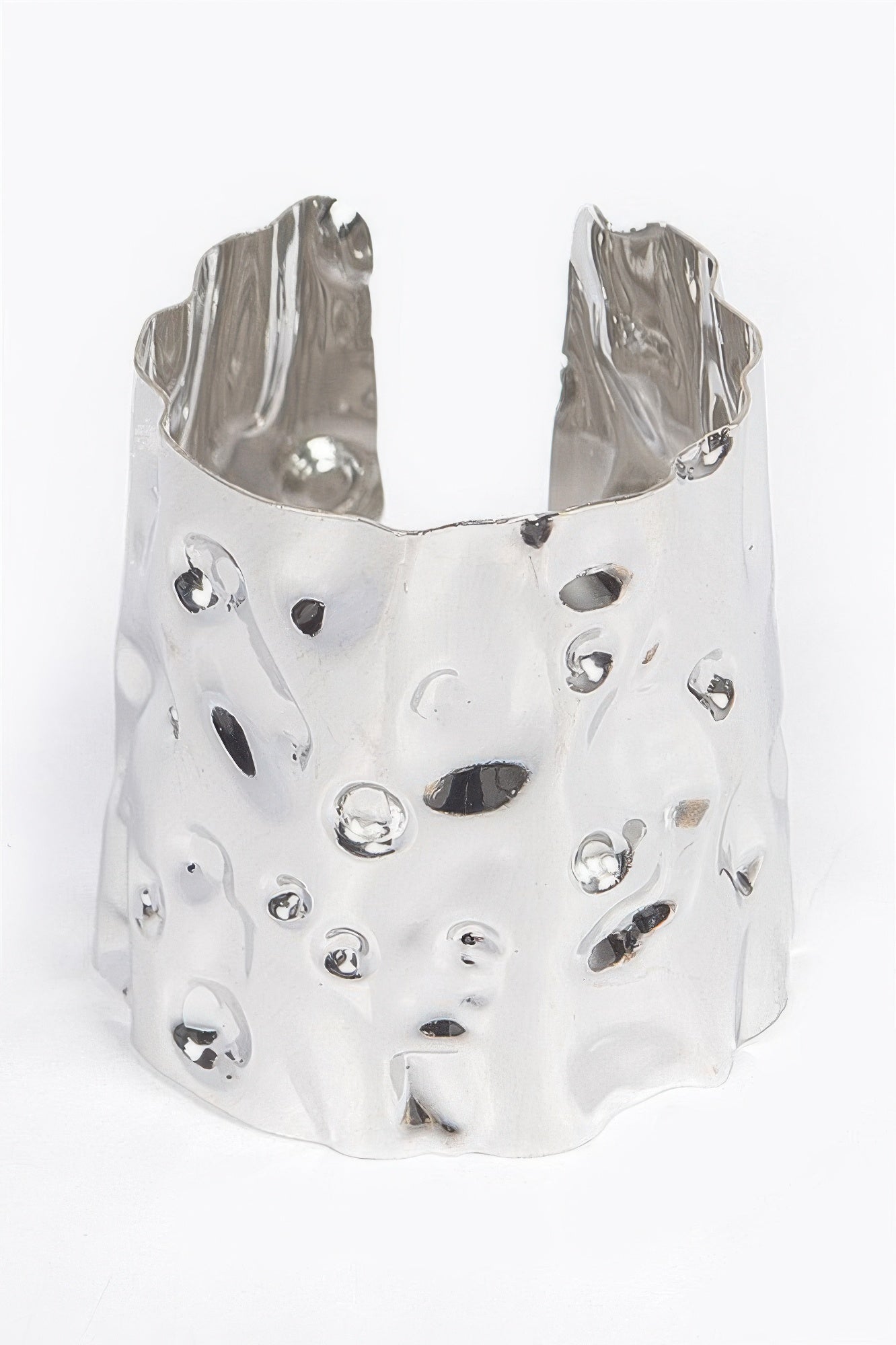 Metal cuff in silver tone with irregular openwork texture and glossy stud insets