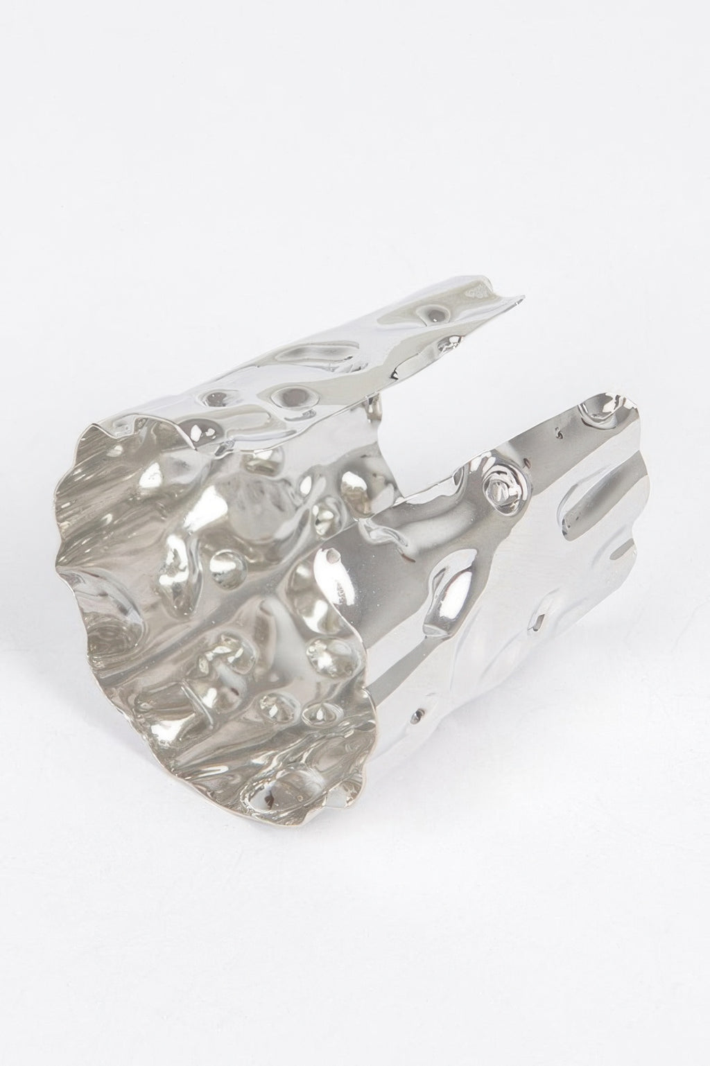 Silver metal cuff, angled view with hammered finish and cutout openings along edge