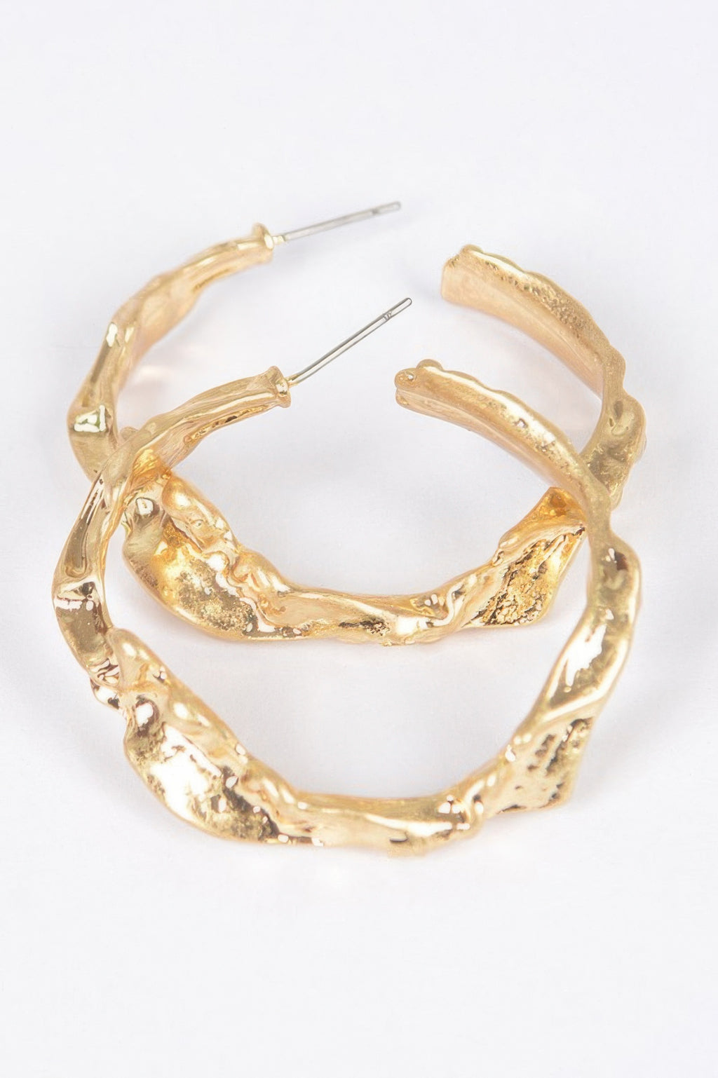 Gold metal hoop earrings with textured, sculpted outer edge and stud posts
