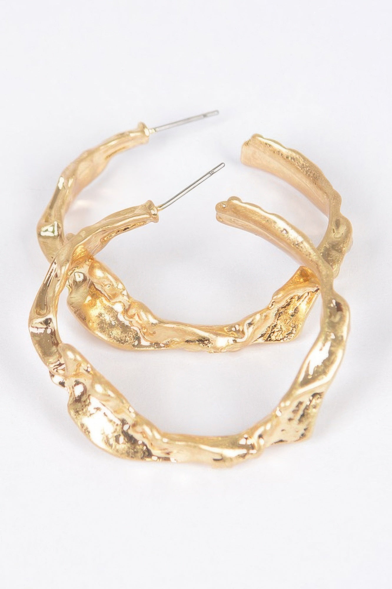 Gold metal hoop earrings with textured, sculpted outer edge and stud posts