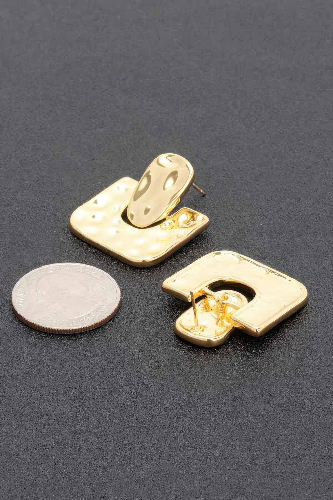Gold dip earring close-up: speckled U-shape post backs, shown with coin for size