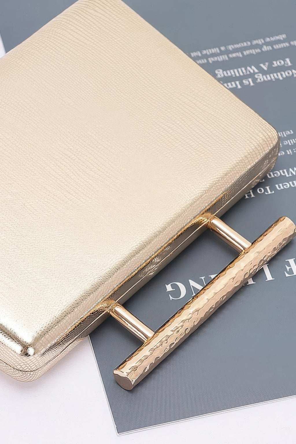 Gold metal handle on textured top case clutch with hinge detail