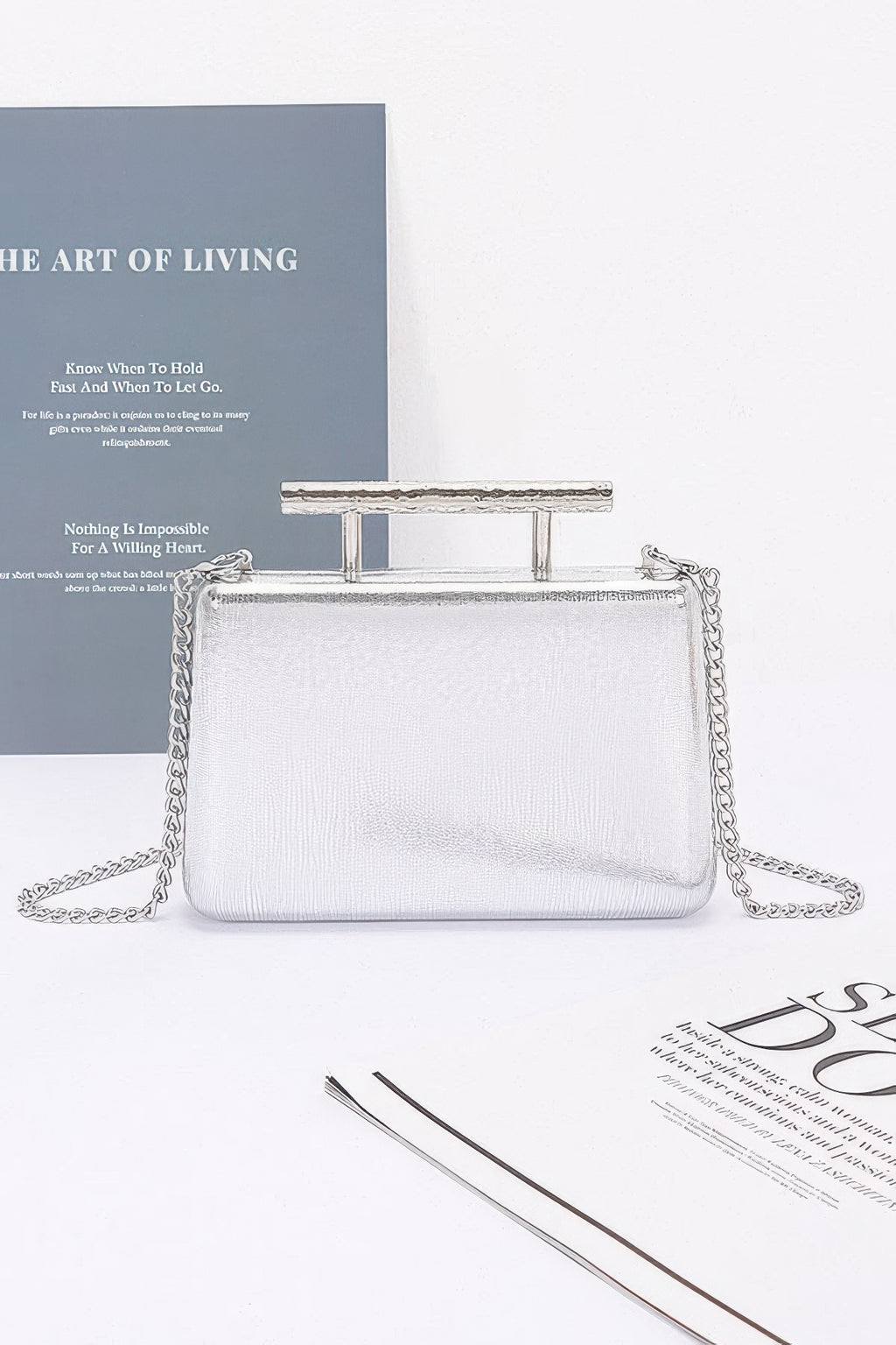 Metal handle top case clutch in silver tone with chain strap and structured shape