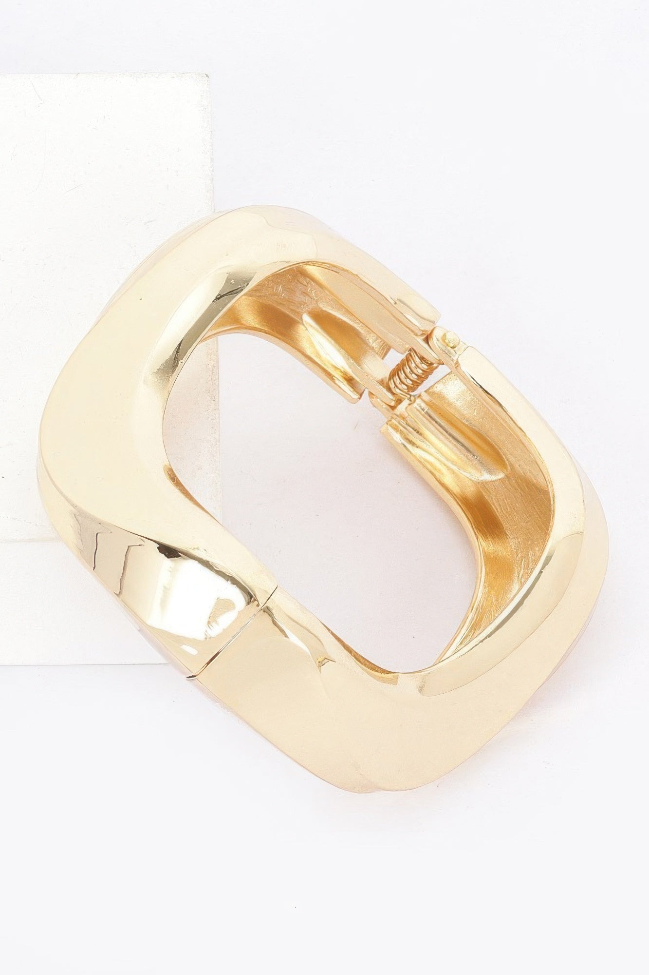 Gold cuff bracelet hinge detail with visible coiled spring inside