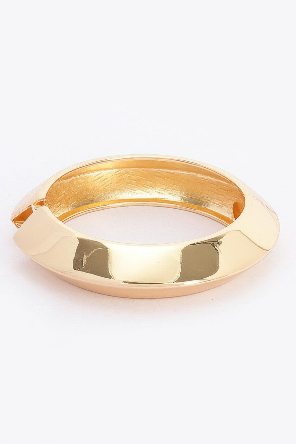 Gold metal spring hinge bracelet with polished curved band and hinged opening.